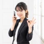 手でOKサインするスーツの女性