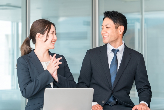 横に並んで話す会社員の男女